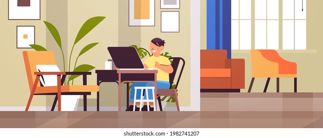 schoolboy at workplace using laptop little boy doing homework education concept living room interior