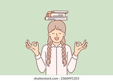 Schoolgirl is meditates standing with books on head and smiling making akasha mudra gesture. Little girl meditates before start lessons in order to learn more knowledge and become leader in school