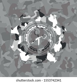 scissors icon inside grey camouflage emblem