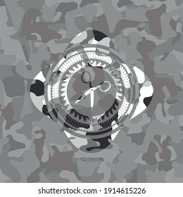scissors icon inside grey camouflaged emblem. 