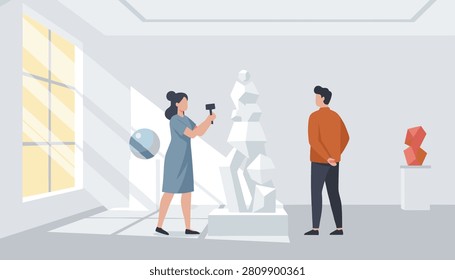 Sculptor works on a geometric stone statue inside a bright art gallery as an interested visitor observes her work.