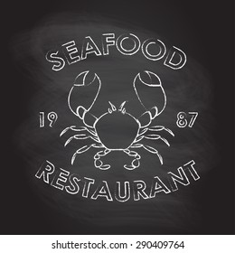 Seafood Restaurant label or emblem with crab symbol. Hand drawn badge or icon in vintage style isolated on blackboard texture. Menu card design element. Vector illustration.  