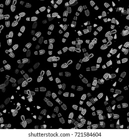 Seamless abstract background of light shoes prints on black.