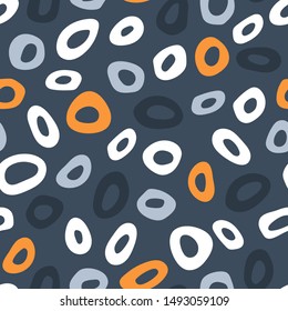 Seamless abstract pattern. Against a dark background, multicolored rings are randomly arranged. Print for textiles and paper. Vector illustration.