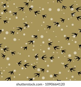 Seamless abstract pattern with silhouettes of flying swallows on gold background and snowflakes.