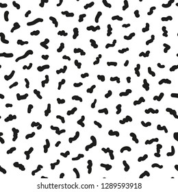 Seamless abstract pattern. Small black scribbles are scattered randomly over a white background. Vector illustration.