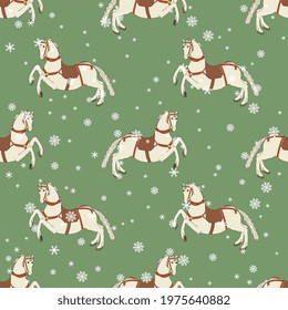Seamless animal winter pattern with running white horses and snowflakes. On green background. Merry Christmas motif.