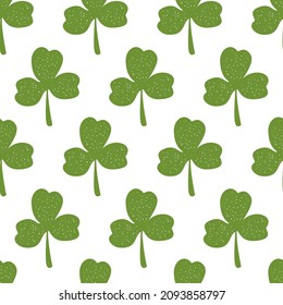 Seamless background with childish simple pattern of clover leaves for St. Patrick's Day. Green primitive shamrocks on a white background. Botanical background for the Irish holiday. 