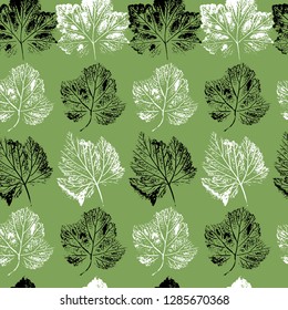 Seamless background of currant and strawberry leaves prints in black and white on green background.