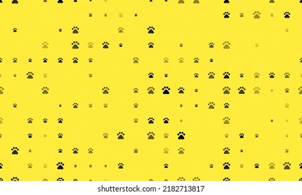 Seamless background pattern of evenly spaced black pet symbols of different sizes and opacity. Vector illustration on yellow background with stars