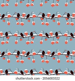 Seamless background from silhouettes sparrows sitting on rowan branches with ripe red berries and snow