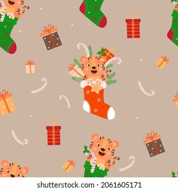 Seamless Christmas pattern with a tiger. Cute tiger cub with a gift and gingerbread with branches of a Christmas tree in a red Christmas sock on background with gifts and caramel. Vector illustration