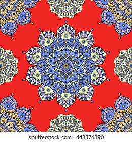 Seamless floral mandala pattern in blue, pale orange, yellow & lavender on bright red background. Vintage vector festive background for paper & textile prints  in oriental / ethnic style.