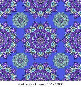 Seamless floral mandala pattern in purple, turquoise green & pale orange on dark royal blue background. Decorative vintage design for textile/paper prints & digital wallpaper backgrounds.