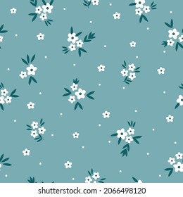Seamless floral pattern. Fashionable background of small white flowers and dots, green leaves. flowers scattered on a light blue background. Stock vector for printing on surfaces and web design.