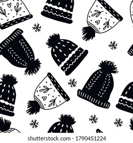 Seamless hand drawn pattern on the theme of New year and Christmas. Knitted hats and snowflakes on white background. Sketch style.