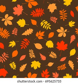 Seamless pattern of autumn colorful leaf silhouettes on brown background. Vector texture for your design