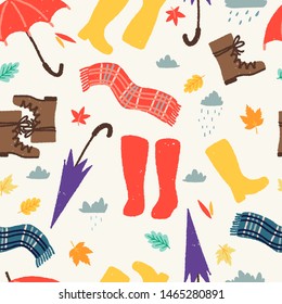 Seamless pattern with autumn essentials for bad fall weather. Rubber boots, scarves, umbrellas and fallen leaves outside in rainy day. Textured flat style wrapping paper, textile or blog wallpaper.