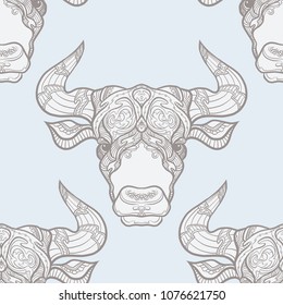 Seamless pattern, background with ethnic patterned ornate hand drawn head of Taurus, bull, ox. On blue vintage  background. 