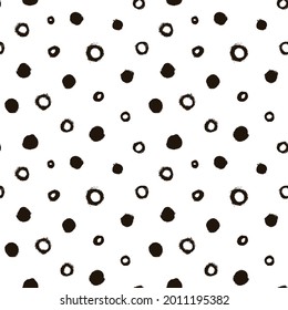 Seamless pattern with black circles scattered on white background. Hand drawn polka dot vector ornament. Modern abstract design for print or textile. Different grunge effect rounded spots and circles