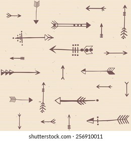 Seamless pattern of brown arrows drawn by hand on beige paper. Vector.
