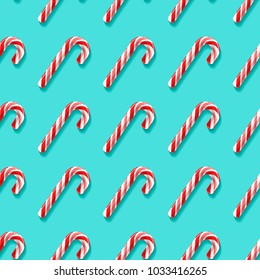 Seamless pattern with candy cane lollypops. Bright red and white elements isolated on spearmint color background. Vector endless design for wrapping, fabric, backdrops