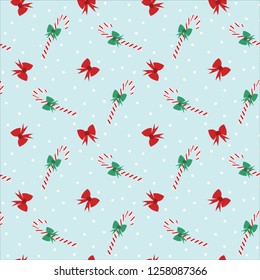 Seamless pattern of candy canes and bows on a blue background with snowflakes. Great for textile print, holiday invitations, wrapping paper, or packaging. Vector file.