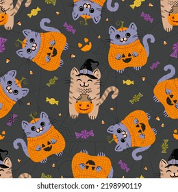 Seamless pattern with cute trick-or-treating cats in Halloween costumes, candies and spiderweb on the dark background