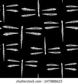 Seamless pattern in the form of flying dragonflies. Pattern in the form of a sketch. Abstraction. White dragonflies on a black background.