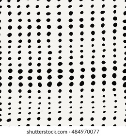 Seamless pattern with irregular dots in black on cream background.