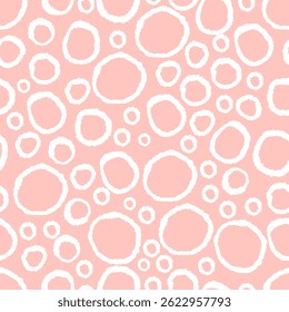 Seamless pattern of irregular white hand-drawn circles on soft pink background. Organic round shapes arranged in dense layout with textured edges. 