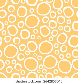 Seamless pattern of irregular white hand-drawn circles on yellow background. Abstract doodle texture. Vector template for design and print