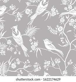 Seamless pattern in oriental style with blooming branches trees and birds. Wildlife silhouette, white floral ornament on gray background. Vector hand drawn illustration, garden in japanese style.