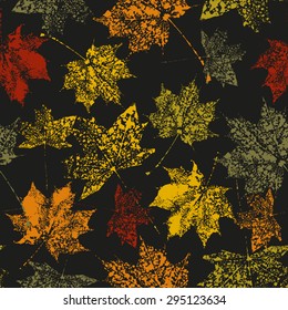 seamless pattern prints maple leaves of orange, terracotta , green and yellow on a black background