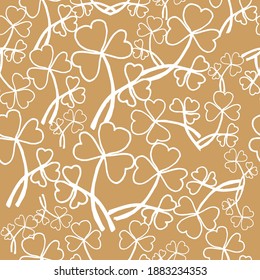 Seamless pattern with randomly repeating white clover leaves on a gold background. Can be used for seasonal design for St. Patrick's day holiday