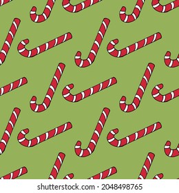Patrón sin foco con caramelos de navidad rojos sobre fondo verde. Imagen vectorial.
