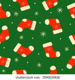 Seamless pattern of red Christmas socks and snowflakes on green background. Doodle style. Christmas winter background. Vector illustration