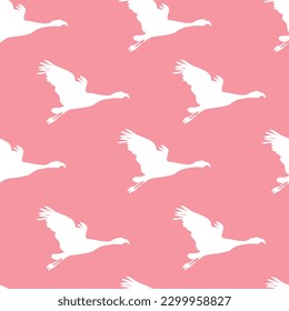 Seamless pattern with silhouettes of flamingos on a pink background.