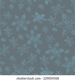 Seamless pattern of swirling in the air blue snowflakes on a grey background