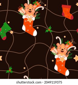 Nahtloses Muster mit Tigern und Weihnachtsdekor. Weihnachtssocke mit lächelndem Tigerbecher, Geschenk, gestreiftem Karamell, Lebkuchen und Weihnachtsbaum auf schwarzem Hintergrund mit Maschenmuster. Vektorgrafik