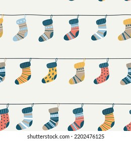 Seamless pattern with warm socks with different texture and color. Vector winter hand drawn socks on a rope. Christmas and Happy New Year background with knitted socks.