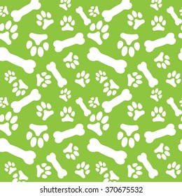 Seamless pattern with white dog paw prints and bones on a green background. Vector illustration