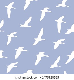 The seamless pattern with white silhouettes of flying birds is on blue background.