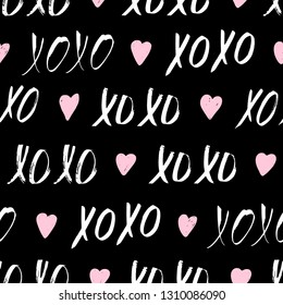 Seamless pattern with XOXO phrase and hearts on black. Romantic theme. Valentines Day background. Vector illustration.