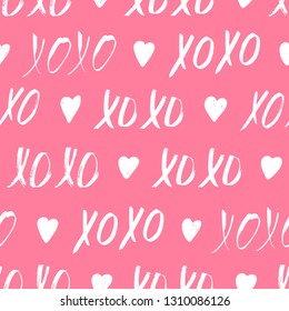 Seamless pattern with XOXO phrase and hearts on pink. Romantic theme. Valentines Day background. Vector illustration.