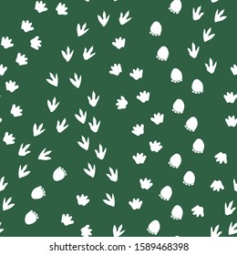 Seamless repeat pattern with different shape white dinosaur foot prints tracks on a green background