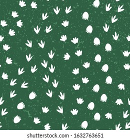 Seamless repeat pattern with different shape white dinosaur foot prints tracks on a green background with a texture