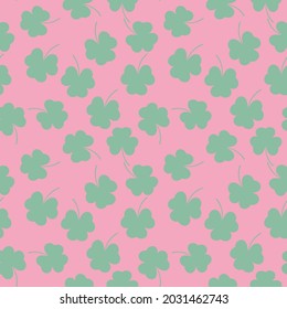 Seamless repeat pattern of scattered green clovers on a pink background
