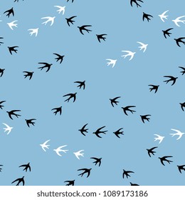 Seamless simple pattern with silhouettes of flying swallow birds.