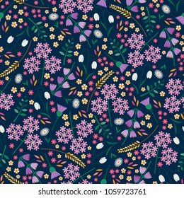 Seamless tossed floral pattern with snowdrops, daisies, angelica, bluebells and thistles on a dark blue background
